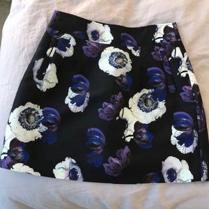 Floral print mini skirt with pockets. 100% polyester. Black, purple, white print